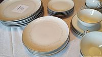 Top view of stacked dinner plates, salad plates, and dessert plates along with coffee cups and saucers set on table.