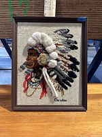 Framed textile art of Native American chief with 3D feathers and signature 'Christine'.