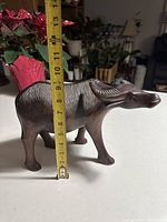 Frontal view of the carved wooden carabao with measuring tape showing about 11 inches tall.