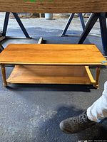 Side angle view of wooden coffee table showing turned legs and lower shelf.