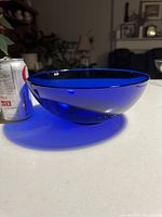 Side view of cobalt blue glass bowl next to a soda can for size comparison