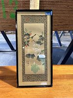 Front view of framed fabric artwork showing flowers and birds with patterned border.