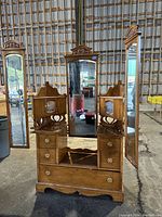 Front view of dresser base with center mirror and open side mirrors.