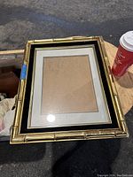 Photo of gold tone bamboo style picture frame on wood surface, with a coffee cup nearby for scale.