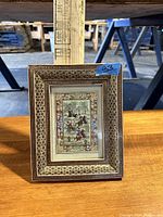 Clear image of framed picture showing detailed equestrian scene and ornate border.