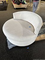 Front view showing white round couch with crescent seat cushion and curved backrest.