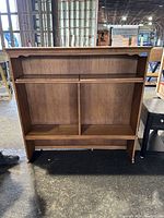 Full view of wooden shelving unit with scalloped top edge and vertical divider