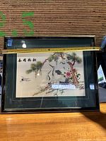 Photo of framed silk embroidery artwork showing cranes, pine tree, flowers, and Asian characters with measuring tape indicating approximately 24.5 inch width.
