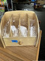 Front view of the wooden box organizer showing four vertical compartments and one single round-knob drawer, wrapped in clear protective plastic.