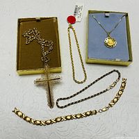 Photo showing all items in the lot including two 10K gold bracelets and several gold-filled cross necklaces, two in boxes.