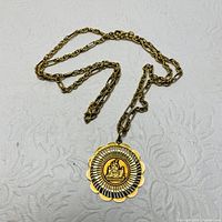 Yellow gold necklace laid flat showing medallion pendant detail and chain.