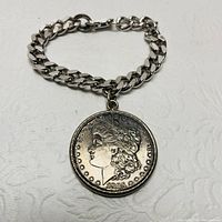 Silver chain bracelet with a large 1885 Morgan silver dollar coin attached, obverse side showing Lady Liberty's profile.