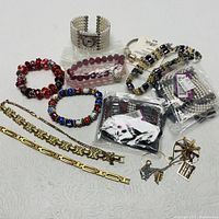 Photo showing various bracelets and wristwatch arranged on table, including packaged and unpackaged items.