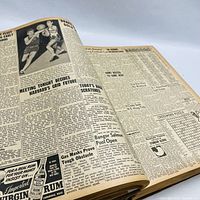 Open book showing newspaper pages with articles, sports news, and advertisements from Boston Evening American April 1943.
