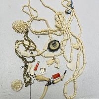 Photo showing full jewelry lot including carved bead necklaces, flower brooches, cameo pendant, and various carved pendants and chains.