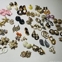 Overview of assorted costume jewelry earrings laid out on white background showing diversity of styles and colors.