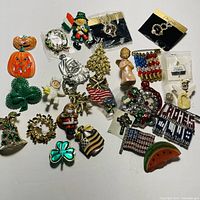 Photo showing the full assortment of holiday and miscellaneous costume jewelry pins laid out on a flat surface.