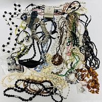Overhead photo of assorted costume jewelry necklaces spread out, showing variety of colors and styles including beaded and chain designs.