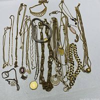 Full view of assorted goldtone costume jewelry necklaces on white background
