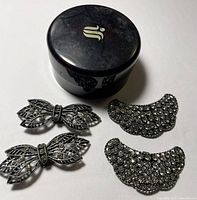Photo showing two pairs of decorative shoe clips and round trinket box.