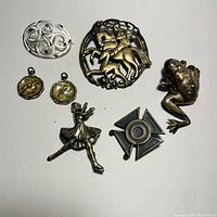 Seven sterling silver pins and pendants arranged showing details and overall lot contents.
