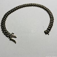 Full view of silver-tone tennis bracelet with cubic zirconia stones laid flat showing overall condition.