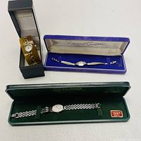 Front view of three watches in their original presentation cases; Vernier in black box, Diamond Goddess in blue velvet case, Dufonte by Lucien Piccard in green case.