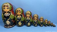 Front view of 9 nesting dolls arranged from largest to smallest showing detailed painted faces and clothing.