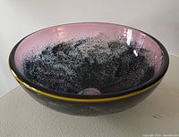 Top view showing the inside coloration and pattern of the purple-pink and black speckled glass bowl with yellow rim.
