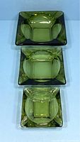 Three vintage emerald green glass ashtrays displayed separately showing nesting sizes from largest to smallest.