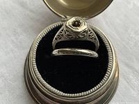 Top-down view of both rings displayed in a small hinged box with black velvet insert