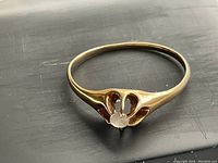 Front view of the antique gold ring showcasing the single diamond and petal-shaped openings in the setting.