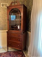 Full front view showing arched glazed door, wood finish and scroll pediment