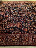Partial view of carpet showing central floral pattern on dark blue field