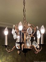 Full view of 5-arm chandelier with bulbs and hanging crystals