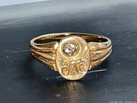 Front view showing bezel-set diamond and engraved letter M on oval face