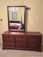 Front view of the walnut dresser with nine drawers and attached mirror showing wood finish, drawer handles, and overall design.