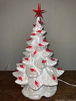 Full view of the vintage white ceramic Christmas tree with red bird-shaped lights and red star topper, plugged in and lit.