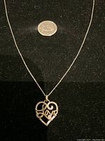 Full view of necklace and pendant on black fabric with US quarter for scale