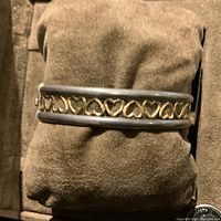 Close-up image showing the bracelet's open heart gold design framed by sterling silver on a brown cushion.