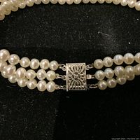 Close‐up of 14K white gold box clasp and attached triple pearl strands