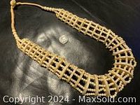 Full view of the large antique carved bead necklace showing the lattice pattern and natural bead variations on a dark background.