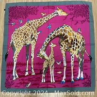 Photo showing the entire square silk scarf laid flat, depicting three giraffes with a magenta background and blue border.