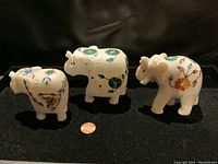 Photo of all three pietra dura carved elephants showing front and side profiles on black background with penny for scale.