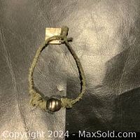 Bracelet laid flat on dark leather surface, showing full length and knot closure