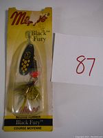 Photo of Mepps Black Fury #3 spinner lure in original blister packaging with yellow cardboard backing showing branding and product details.