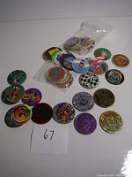 Multiple Pogs and slammers spread out with visible colorful designs and holographic effects