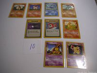 Nine Pokemon cards from 1999 Unlimited Base Set laid out on white surface showing artwork and text of each card.