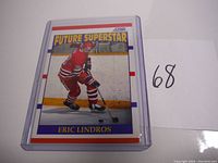 Front of 1990 Score Eric Lindros Future Superstar rookie hockey card showing Eric Lindros skating in a red uniform on ice, card is encased in protective plastic.