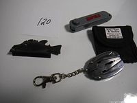 Overview photo showing all three items: fish-shaped line trimmer, Rapala multi-tool, and Jig-Eye Buster with pouch